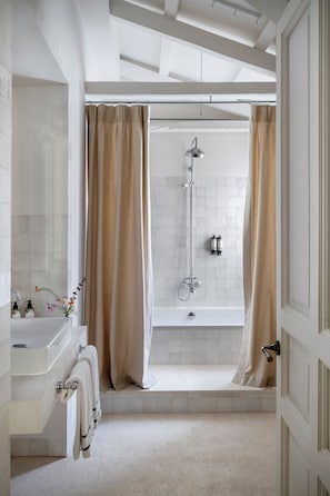 Une salle de bain moderne équipée d’une baignoire, d’une douche et d’un meuble-lavabo avec un évier et un porte-serviettes.