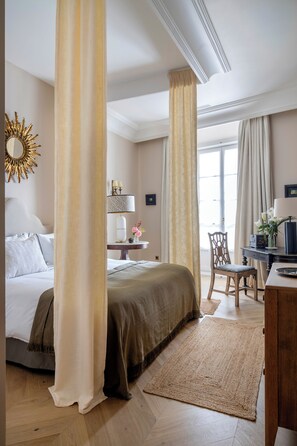 Una habitación de hotel con cama, escritorio, silla, espejo y ventana.