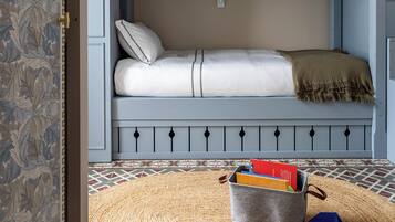 A room with a bunk bed, a woven rug, and a storage basket.