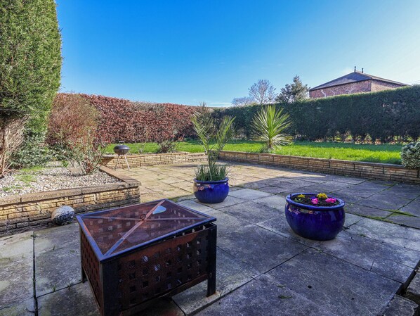 A patio with a metal table, potted plants, and a brick wall.