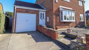 A two-story brick house with a white garage door and a small attached garage. - Thorntons House (Northallerton)
