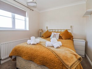 A neatly made bed with a quilted blanket, two pillows, and a bedside lamp.