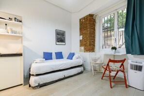 Ein kleines Zimmer mit Bett, Schreibtisch, Stuhl und Heizkörper.