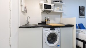 A compact hotel room with a washing machine, a microwave, and a small sink. - M Piz401 Acogedor Estudio en el Centro de Madrid (Madrid)