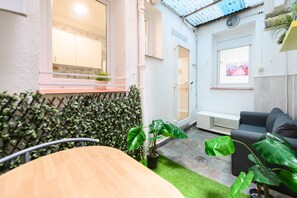 Ein modernes Interieur mit einem Holztisch, einem grauen Sofa und Grünpflanzen.