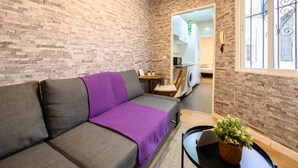 A cozy room with a grey sofa, a purple throw, and a potted plant. - M Jpa16bi Acogedor Piso 1 Dormitorio en Tetu n (Madrid)