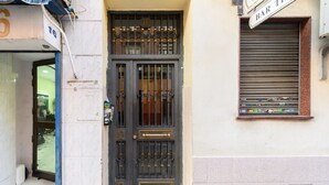 A building entrance with a metal gate, a window with a sign, and a tiled floor. - M Jpa16bi Acogedor Piso 1 Dormitorio en Tetu n (Madrid)