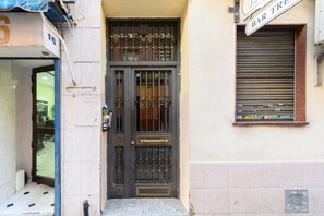 A building entrance with a metal gate, a window with a sign, and a tiled floor. - M Jpa16bi Acogedor Piso 1 Dormitorio en Tetu n (Madrid)
