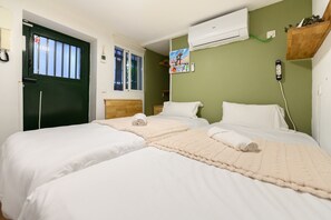 A room with two beds, a green wall, an air conditioner, a wooden shelf, and a window with blinds. - M Svf1304 Acogedor Estudio en Centro de Madrid (Madrid)