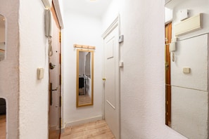 A narrow hallway with a wooden floor, a white door, and a mirror on the wall. - M Por183d Amplio Piso 2 Dormitorios en La Latina (Madrid)