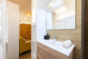 Ein modernes Badezimmer mit einem weißen Waschbecken, einem Spiegel und einer Holzausstattung.