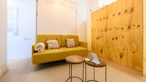 A modern living room with a yellow sofa, two small round tables, and a wooden accent wall. - M Fga50e Acogedor d Plex en Chamber (Madrid)