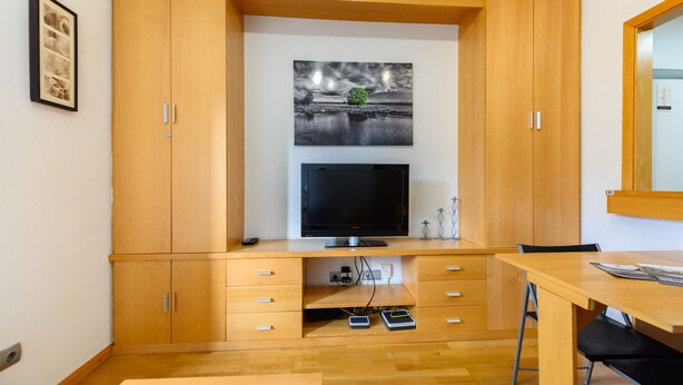 Een moderne kamer met een houten kast, een flatscreen televisie en een eethoek.