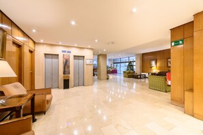 Eine Hotelhalle mit Marmorboden, Holzvertäfelung, einer Rezeption und einem Weihnachtsbaum.