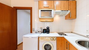 A compact kitchen with a washing machine, a microwave, and a coffee maker. - M Mle16a2320 Amplio Piso 1 Dormitorio en Chamart (Madrid)