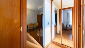 A room with a wooden door, a mirror, a dining table with chairs, and a view of another room with a chair. - M Mle16a2320 Amplio Piso 1 Dormitorio en Chamart (Madrid)