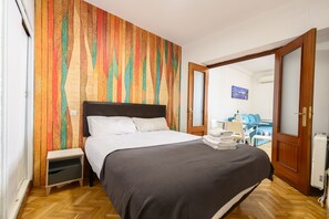 A bedroom with a bed, wooden floor, and a colorful wall. - M May613 Piso de 1 Dormitorio en Pleno Centro de (Madrid)