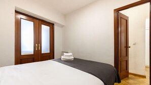 A hotel room with a bed, a wooden wardrobe, and a door leading to another room. - M May613 Piso de 1 Dormitorio en Pleno Centro de (Madrid)