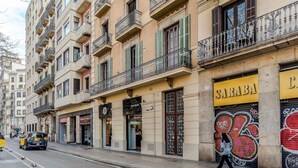 Rua com edifícios, uma pessoa caminhando e um carro.