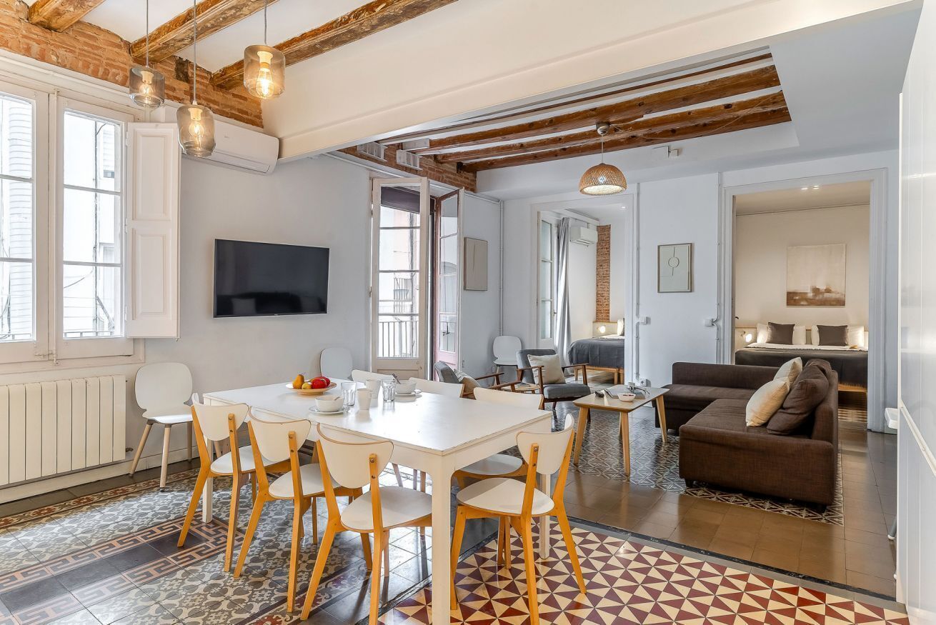 A modern living space with a dining area, a sofa, and a TV mounted on the wall.
