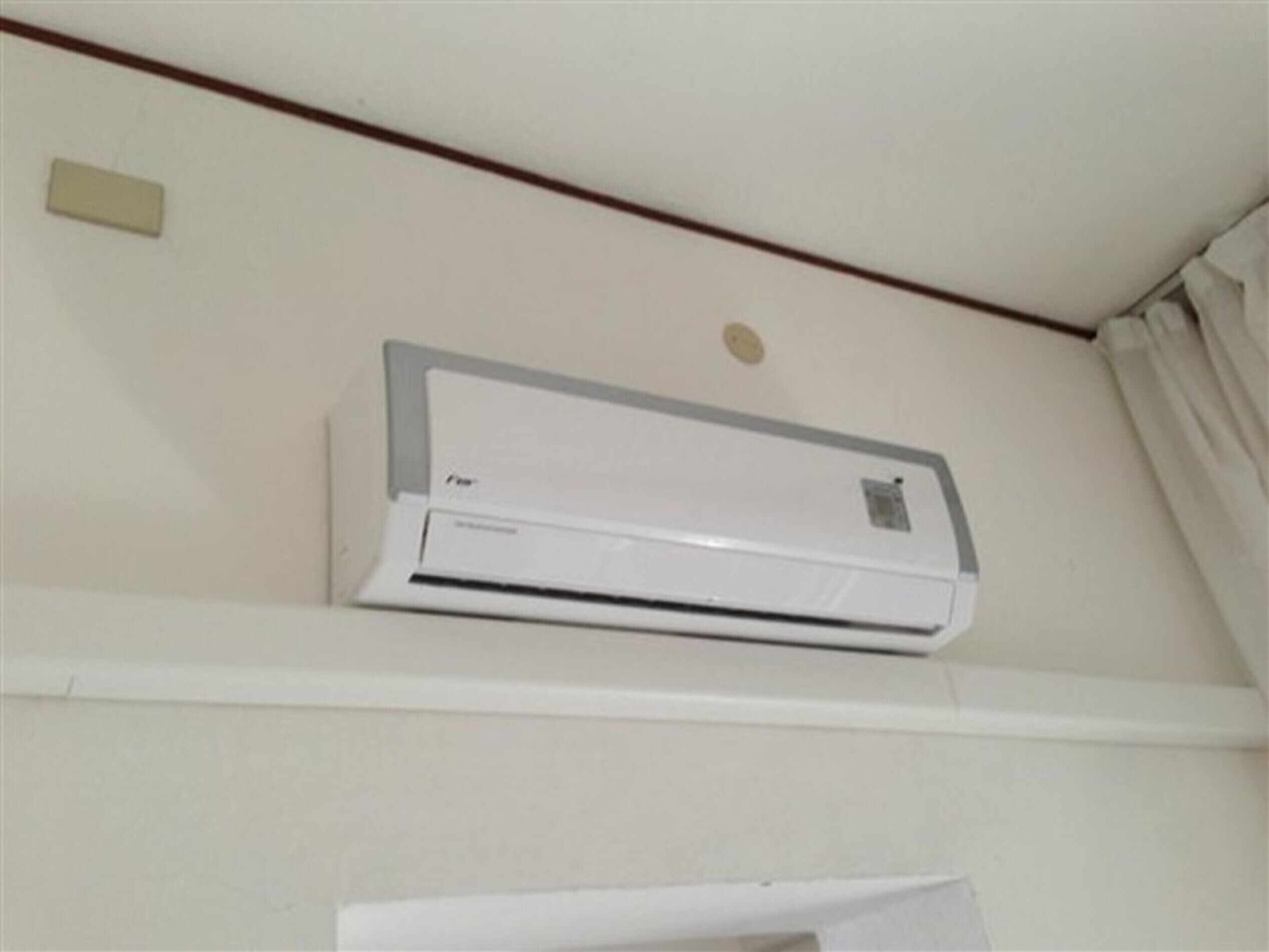 A white air conditioning unit mounted on a wall with a visible control panel and a small vent.