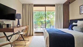 A hotel room with a bed, a desk, a TV, and a view of the outdoors.