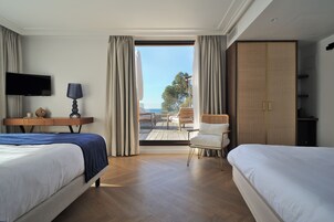 Habitación de hotel con dos camas, un escritorio, un televisor y vista al exterior.