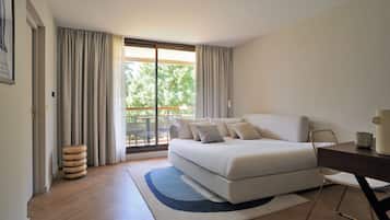 A bedroom with a large bed, a desk, and a view of the outdoors.