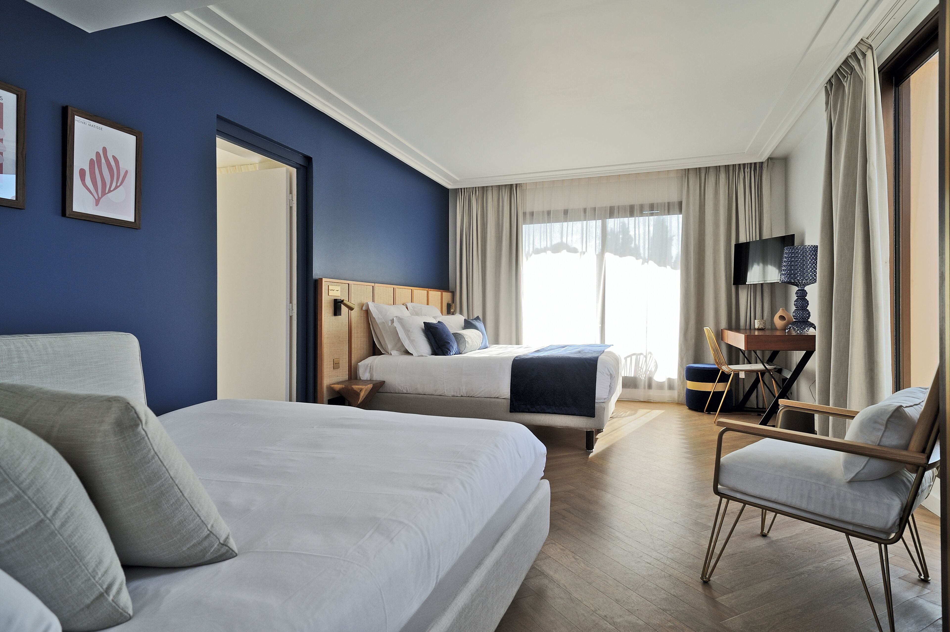 Een hotelkamer met twee bedden, een bureau, een stoel en een televisie.
