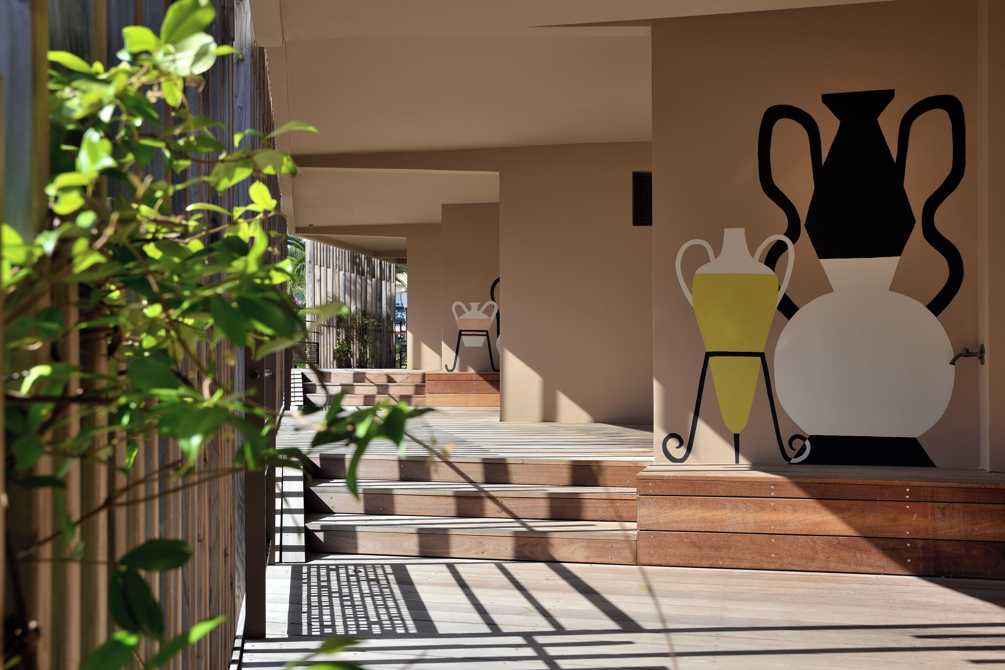 A modern outdoor area with steps leading to a seating area, a wall-mounted planter, and a metal chair.