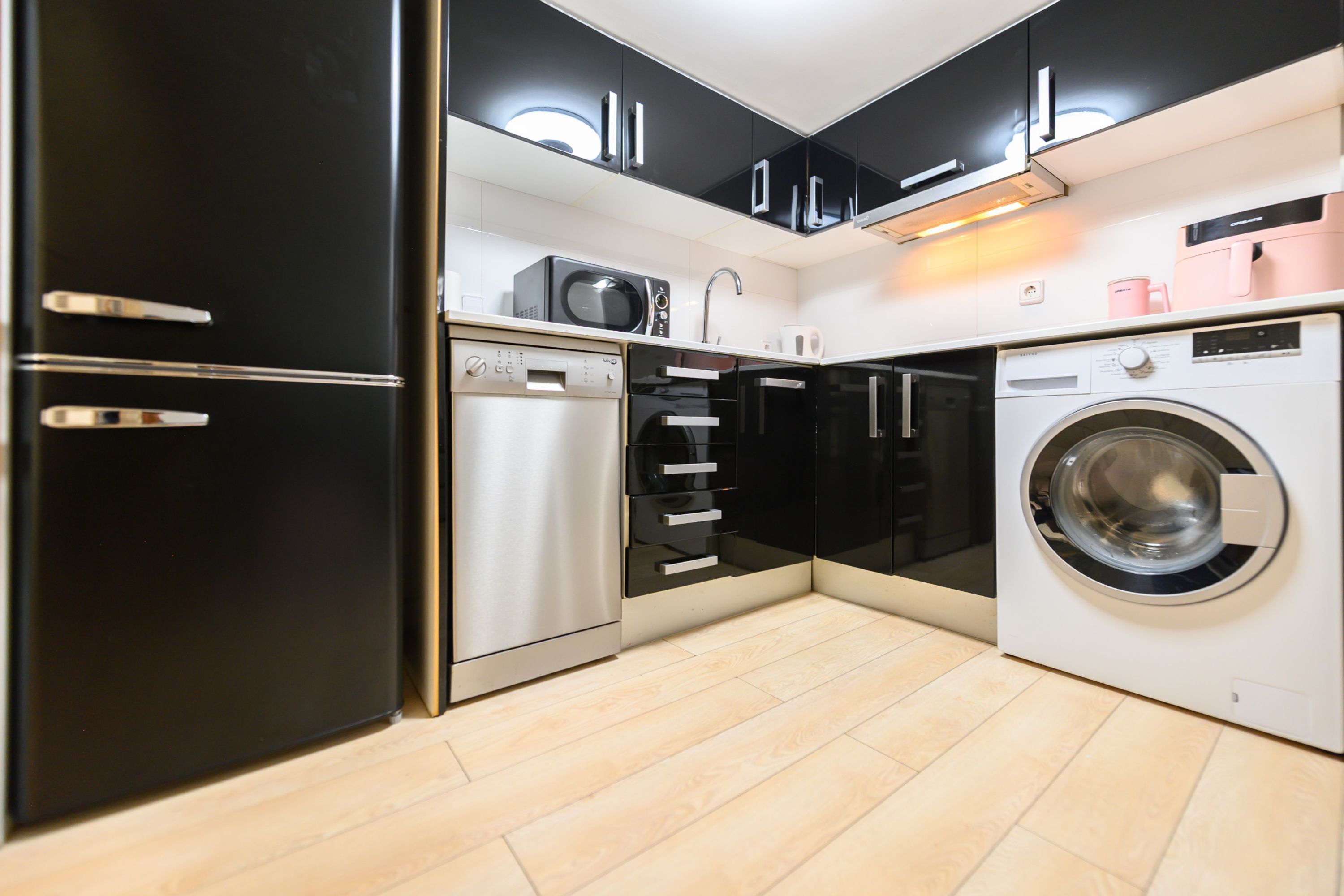A compact kitchen with a dishwasher, microwave, and washing machine.