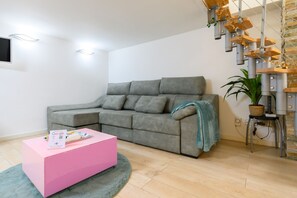 A modern living room with a grey sectional sofa, a pink ottoman, and a green plant. - M Hor291 Moderno d Plex de 1 Dormitorio con Toda (Madrid)
