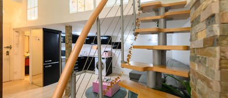 Un interior moderno con una escalera en espiral, una zona de cocina y un espacio de estar con un sofá y una mesa de centro.