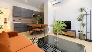 A modern living room with a sofa, a coffee table, a TV, and a dining area with chairs and a table. - M Agu230 Tu Hogar en la Ciudad Piso de 3 Habita (Madrid)