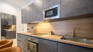 A modern kitchen with stainless steel appliances, a wooden countertop, and a built-in oven. - M Agu230 Tu Hogar en la Ciudad Piso de 3 Habita (Madrid)