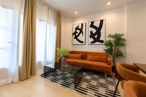 A modern living room with a sofa, a coffee table, and a plant. - M Agu230 Tu Hogar en la Ciudad Piso de 3 Habita (Madrid)