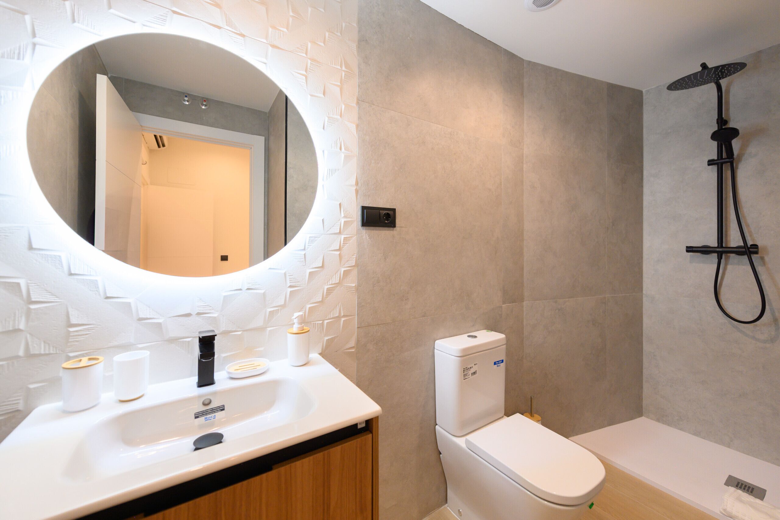 Un baño moderno con lavamanos blanco, inodoro y ducha.