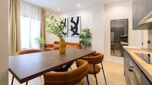 A modern kitchen with a wooden table and chairs, a built-in oven, and a large window with curtains. - M Agu230 Tu Hogar en la Ciudad Piso de 3 Habita (Madrid)