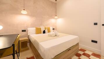 A modern bedroom with a wooden bed, a small desk, and two pendant lights.