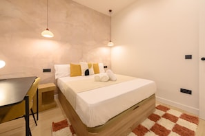 A modern bedroom with a wooden bed, a small desk, and two pendant lights. - M Agu230 Tu Hogar en la Ciudad Piso de 3 Habita (Madrid)