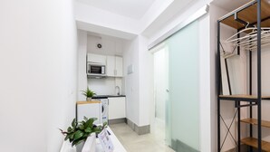 A modern kitchen with white cabinets, a microwave, and a washing machine. There is a plant on the counter and a sign with Google branding. - M Rjs3 Acogedor Estudio en Barrio Salamanca (Madrid)