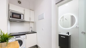 A compact kitchen with a microwave, washing machine, and a sink with a modern vanity. - M Rjs3 Acogedor Estudio en Barrio Salamanca (Madrid)