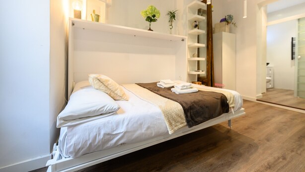 A modern hotel room with a bed, bedside tables, a mirror, and a wooden floor. - M Hor42da Estudio Moderno en el Centro de Madrid (Madrid)