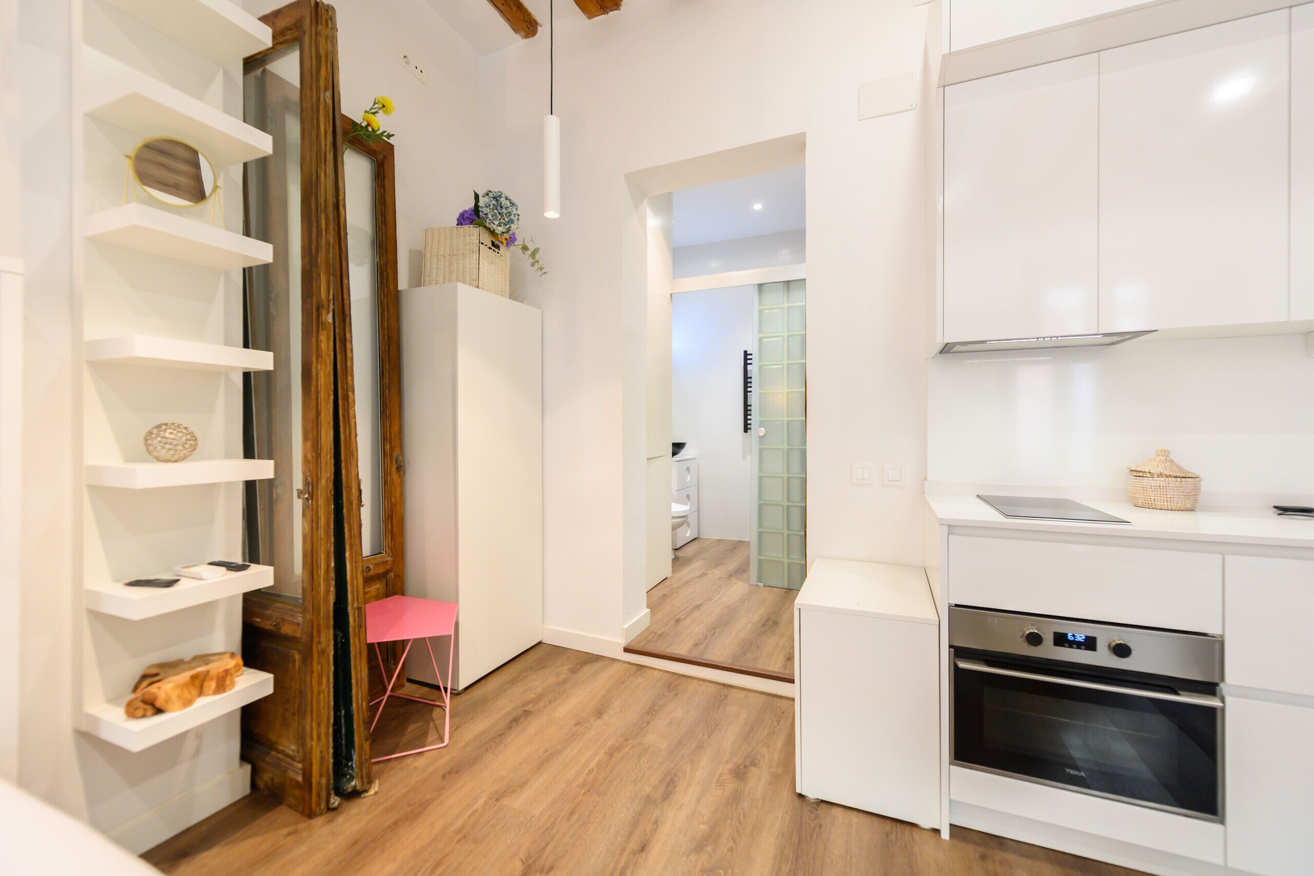 Una cocina moderna con armarios blancos, horno integrado y piso de madera.
