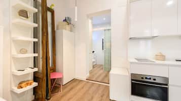 Una cocina moderna con armarios blancos, horno integrado y piso de madera.