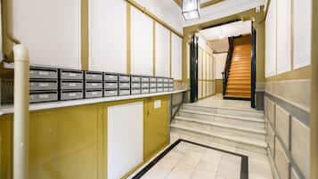 A hallway with a staircase leading to a landing. There are storage cabinets along the wall and a row of mailboxes.