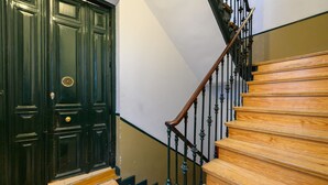 A staircase with wooden steps and black metal railings, leading to a dark green door with a circular window. - M Hor42da Estudio Moderno en el Centro de Madrid (Madrid)