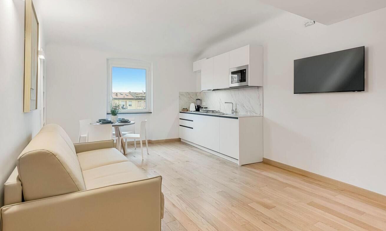 Un appartement moderne comprenant un espace de vie, une kitchenette et un téléviseur fixé au mur.