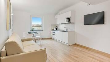 Un appartement moderne comprenant un espace de vie, une kitchenette et un téléviseur fixé au mur.