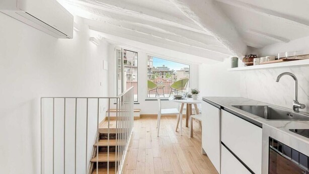 Una cocina moderna con estufa integrada, un lavamanos y ventana con vistas a un balcón.